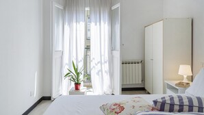 A bedroom with a bed, a bedside table with a lamp, a wardrobe, and a window with curtains. - A Pochi Passi da Piazza de Ferrari (Genoa)