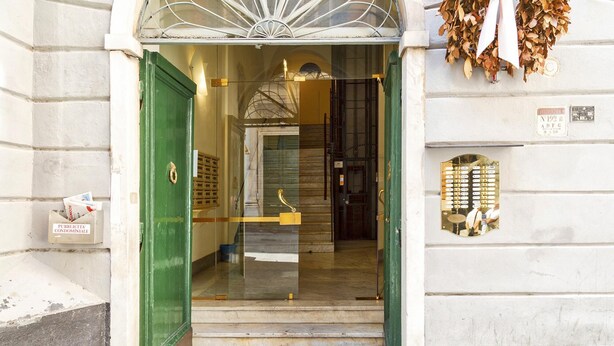 A building entrance with a green door, a glass door, and a metal gate. - A Pochi Passi da Piazza de Ferrari (Genoa)