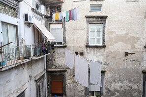 A narrow urban alley with old buildings, balconies, and laundry hanging between them.