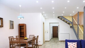 A spacious living area with a dining table, chairs, a blue sofa, and a staircase. - Tribunali Family Apartment by Wonderful Italy (Naples)