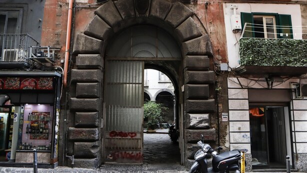 An arched entrance to a building with a scooter parked in front. - Tribunali Family Apartment by Wonderful Italy (Naples)