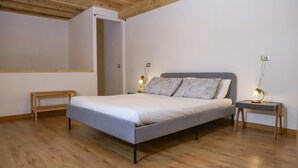 A bedroom with a bed, bedside tables, a wooden floor, and a wooden ceiling. - Tribunali Family Apartment by Wonderful Italy (Naples)