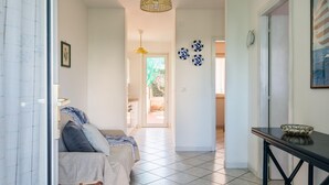 A hallway with a bed, a table, and a door leading to a kitchen. - White Sea by Wonderful Italy - Villetta Aurora (Carovigno)