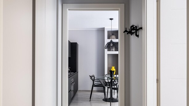 A narrow hallway leading to a kitchen with a dining area.