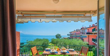 Un balcone con un tavolo apparecchiato per mangiare, affacciato su un corpo d'acqua e edifici.