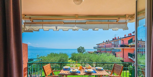 A balcony with a table set for dining, overlooking a body of water and buildings.