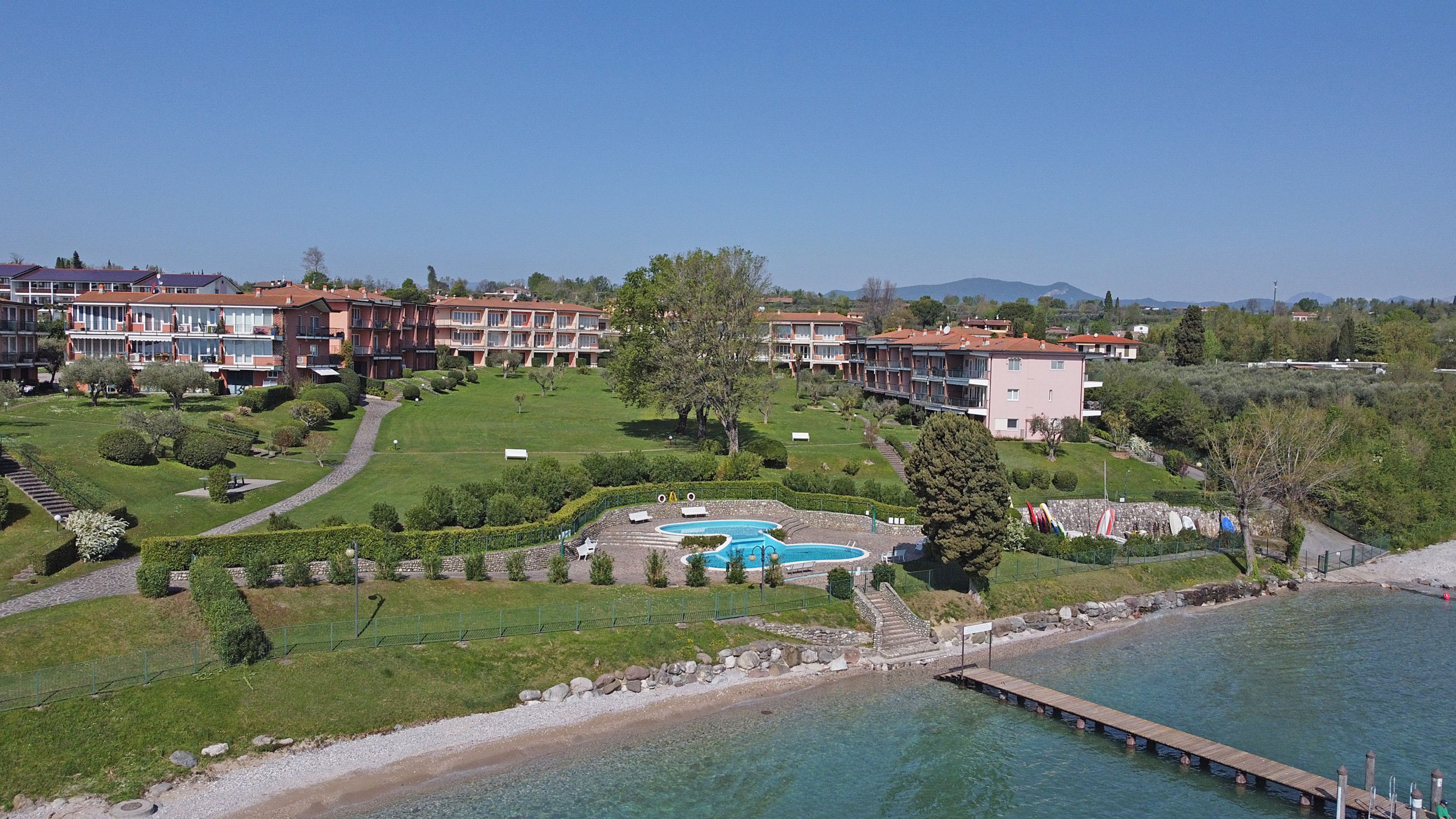 A resort with a swimming pool, multiple buildings, and a dock by the water.