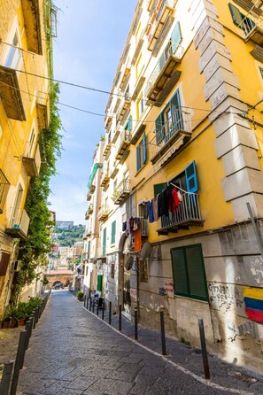 A narrow cobblestone street flanked by multi-story buildings with balconies, some with clothes hanging out to dry. - Appartamento a Montesanto by Wonderful Italy (Naples)