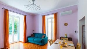Une pièce avec un canapé de couleur turquoise, une table à manger dressée avec des assiettes et des verres, et un lustre moderne.