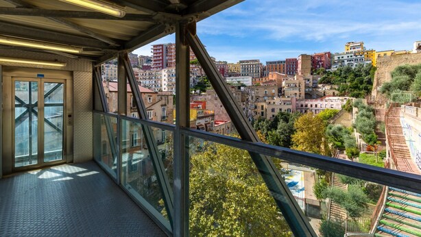 Un balcon offrant une vue sur le paysage urbain, avec des bâtiments et de la verdure.