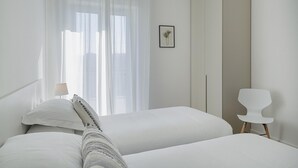 Un dormitorio minimalista con dos camas, un armario grande y una sola silla.