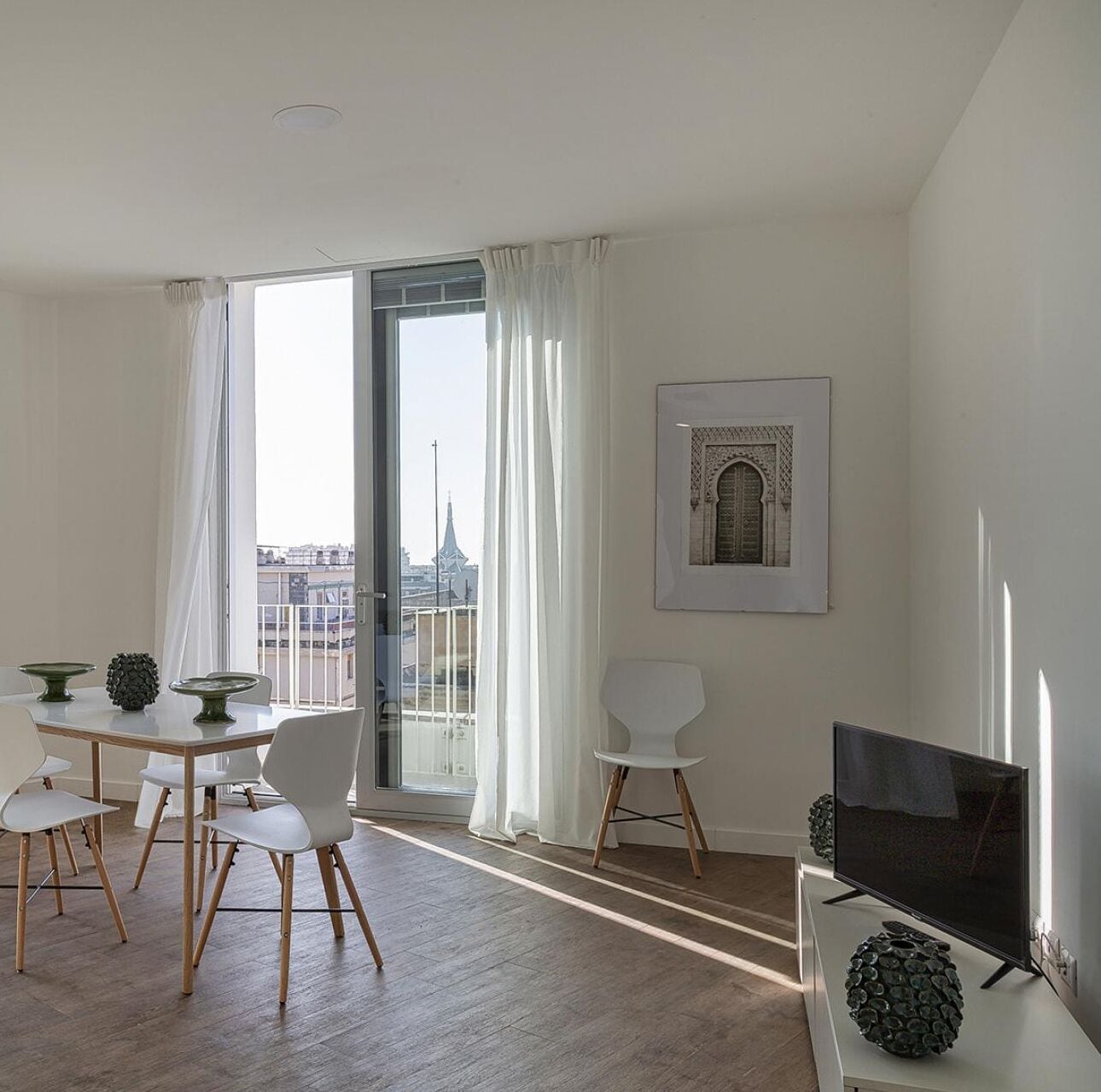 A modern living room with a dining area, a TV, and a balcony with a city view.