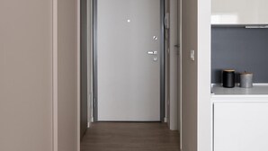A narrow hallway with a door at the end, a white cabinet with a black object on top, and a ceiling-mounted air conditioning unit. - Studio Green al Parco by Wonderful Italy (Bologna)
