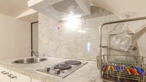 A kitchen with a double sink, a stove, and a dish rack with utensils.