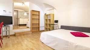 A hotel room with a bed, a TV, a desk, and a chair.