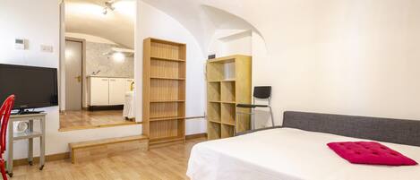 A hotel room with a bed, a TV, a desk, and a chair.