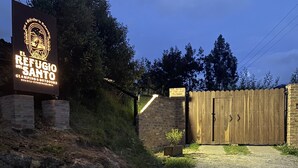 Une enseigne indiquant « El Refugio del Santo », avec une porte en bois et un mur en briques.