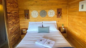 Une pièce de style cabane en bois, avec un lit, deux assiettes décoratives accrochées au mur et une table de chevet avec un verre.