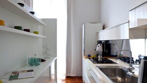 A modern kitchen with white cabinetry, a stainless steel sink, and a gas stove. - Elegant Apartment at Chiaia by Wonderful Italy (Naples)