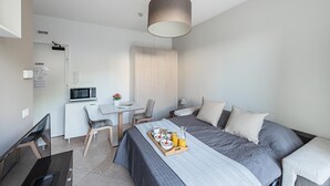 A modern hotel room with a bed, a desk, a chair, and a dining table set with breakfast. - Residenza Miralago With Pool - Ground Floor Studio Apartment (Desenzano del Garda)