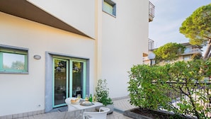 A modern apartment with a balcony, a dining area with outdoor seating, and a view of neighboring buildings. - Residenza Miralago With Pool - Ground Floor Studio Apartment (Desenzano del Garda)
