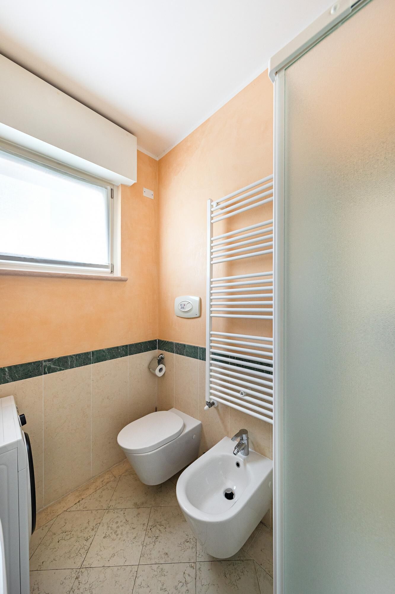 Un baño pequeño con inodoro, bidé y ventana.