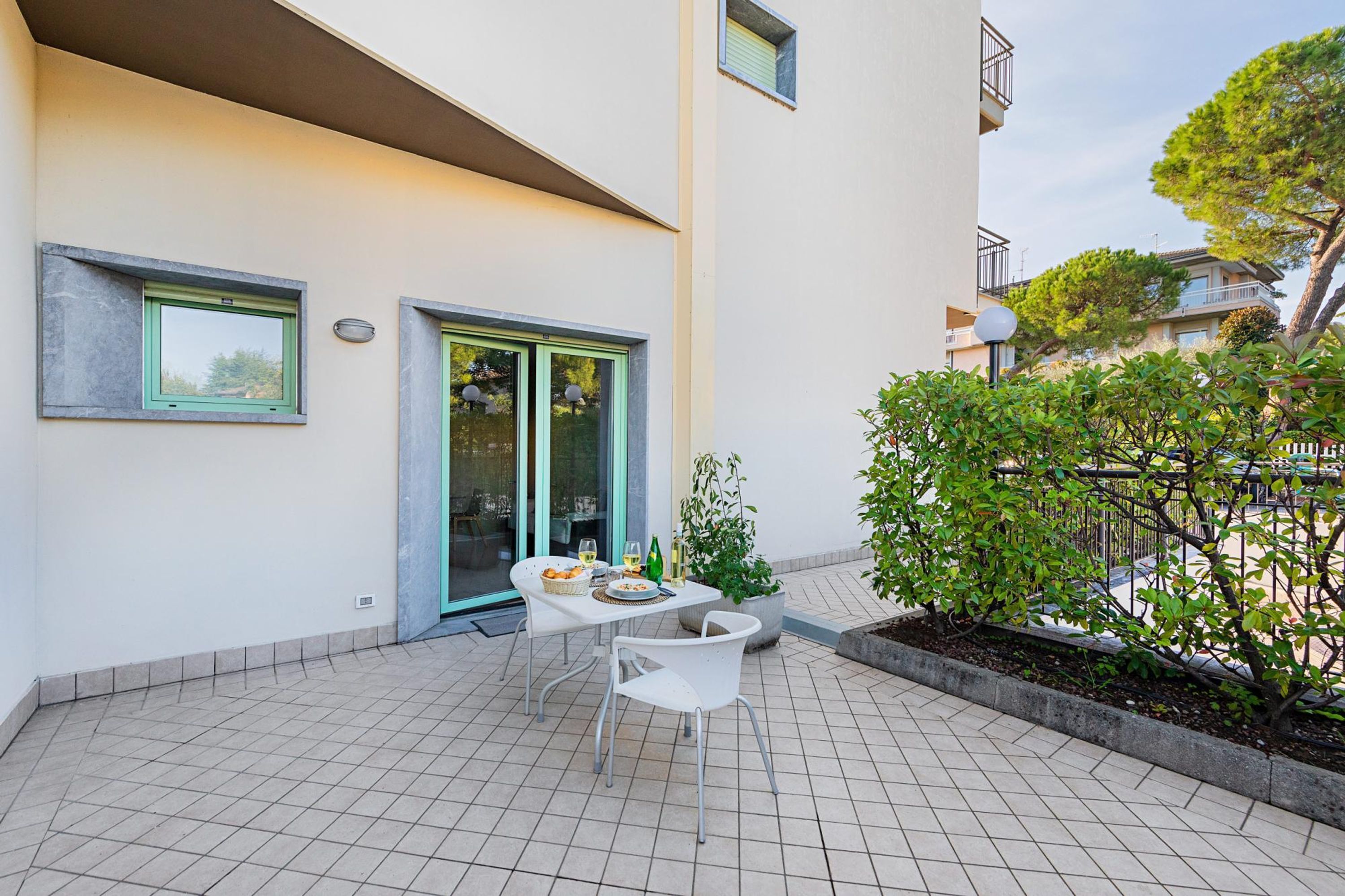 A modern outdoor patio with a tiled floor, a table with chairs, and a potted plant.