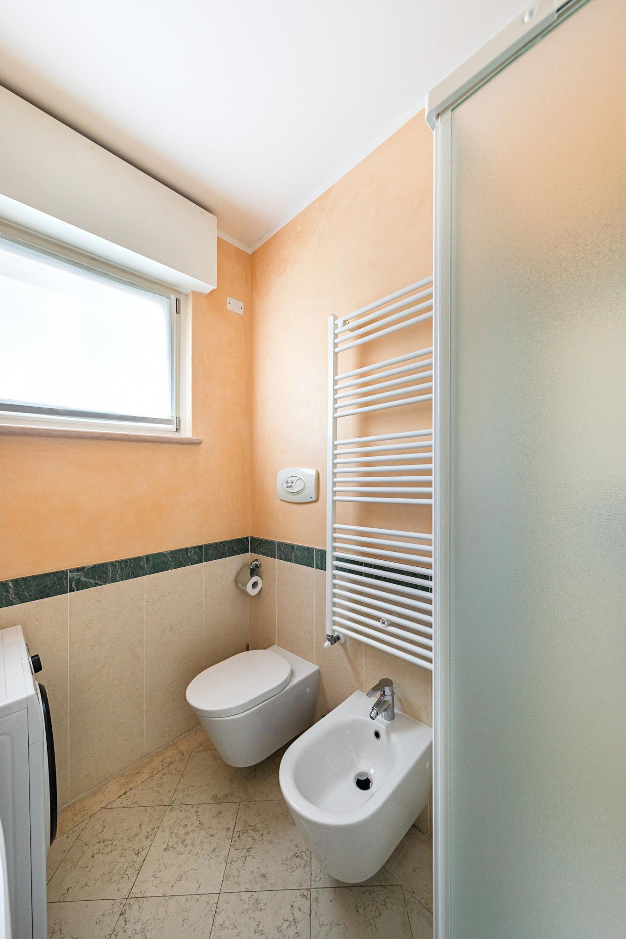 A small bathroom with a toilet, bidet, and a towel rack.