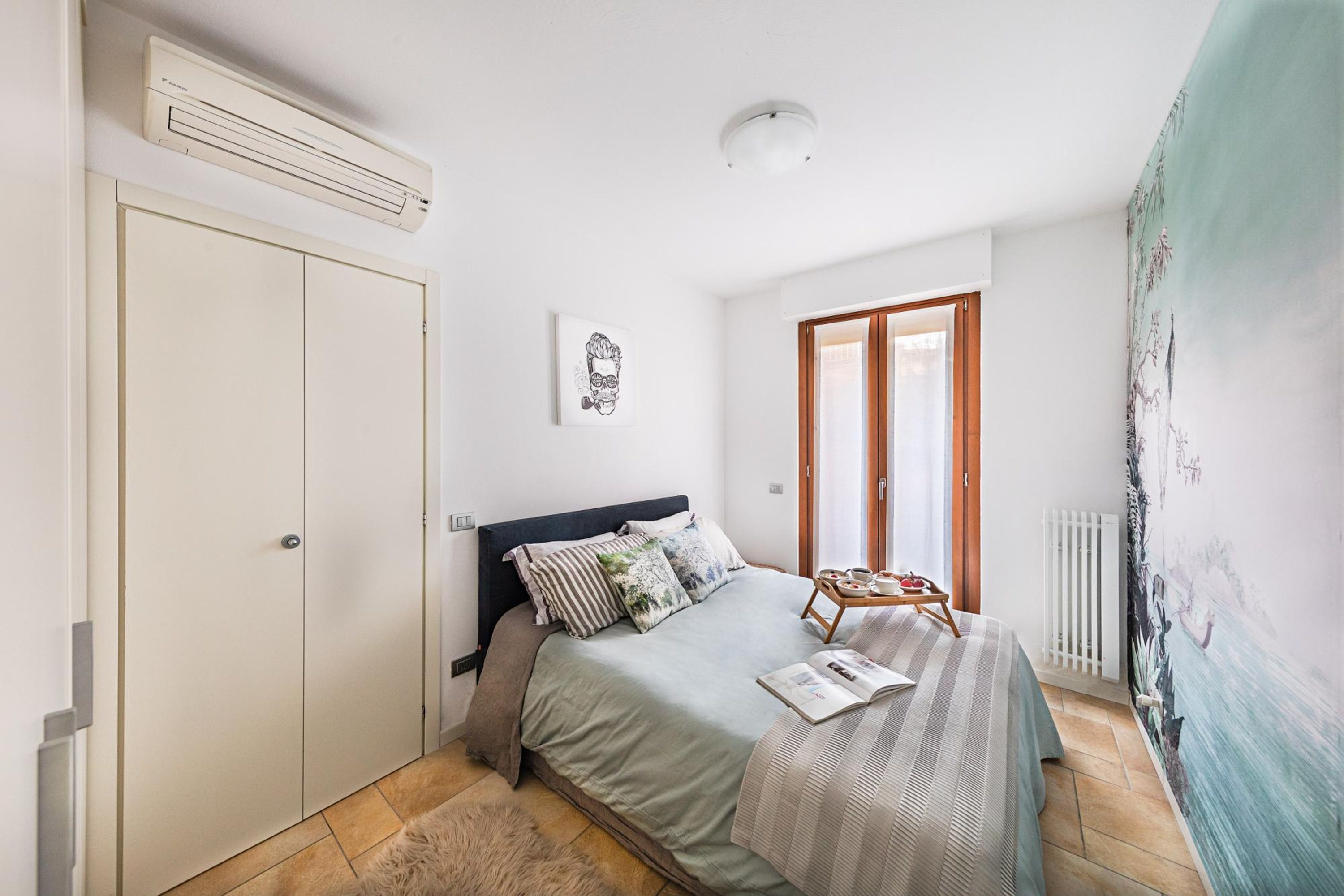 Une chambre à coucher avec un lit, une armoire, un radiateur et une fenêtre.