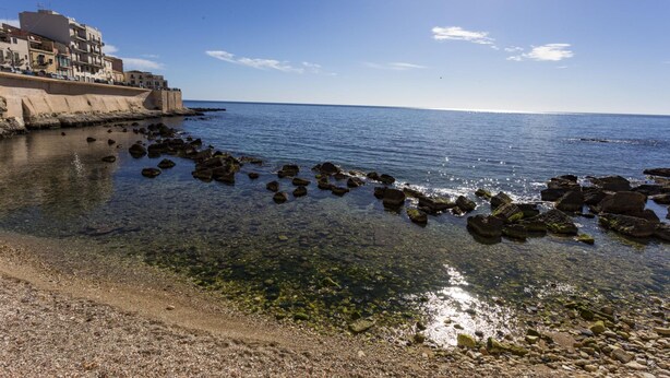 Paisaje costero con vista despejada al mar, costa rocosa y edificios a lo largo de la costa.