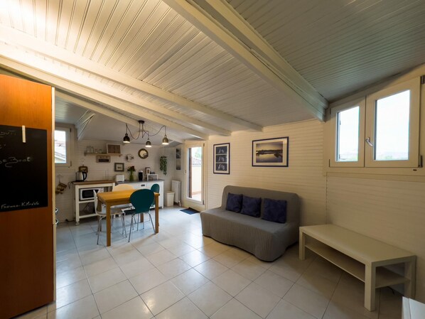 A cozy, well-lit room with a dining area, a sofa, and a bench.