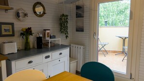 A compact kitchen with a dining area, a window with a view of greenery, and a small outdoor seating area.
