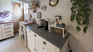 A kitchen with white cabinets, a countertop, a kettle, a coffee machine, and a hanging plant.