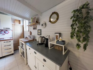A kitchen with white cabinets, a countertop, a kettle, a coffee machine, and a hanging plant.