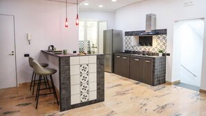 Een moderne keuken met een centraal eiland, een paar barkrukken, een inbouwfornuis en een roestvrijstalen koelkast.