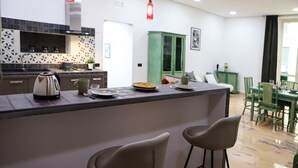Een moderne keuken met een centraal eiland, barstoelen en een eethoek met groene stoelen.