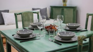 Een eettafel gedekt met kommen, glazen en bestek, omringd door groene stoelen.