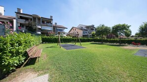 A well-maintained grassy area with a swing set, a paved path, and a bench. - Mandorli 1 18 Apartment by Wonderful Italy (Desenzano del Garda)