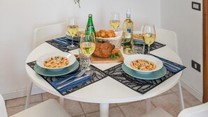 A dining table with plates of pasta, glasses of wine, and a bottle of beer. - Mandorli 1 18 Apartment by Wonderful Italy (Desenzano del Garda)