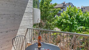 A balcony with a round table and chairs, a railing, and a view of buildings and trees. - Mandorli 1 18 Apartment by Wonderful Italy (Desenzano del Garda)