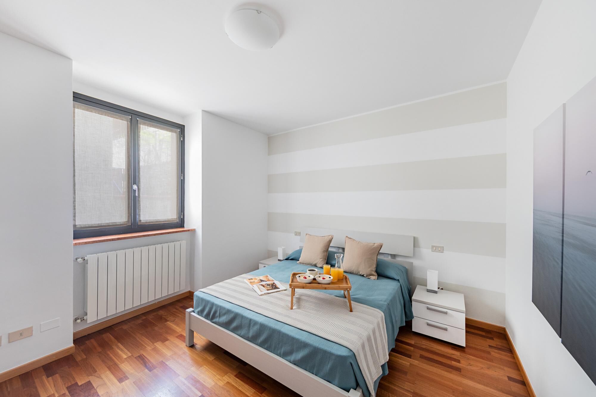 A bedroom with a bed, bedside table, and a window.