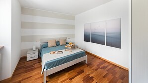 Une chambre à coucher comprenant un lit, des tables de chevet, une commode et une œuvre d’art accrochée au mur.