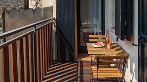 Une terrasse en bois avec une table et des chaises, une bouteille de vin et un verre posé sur la table.