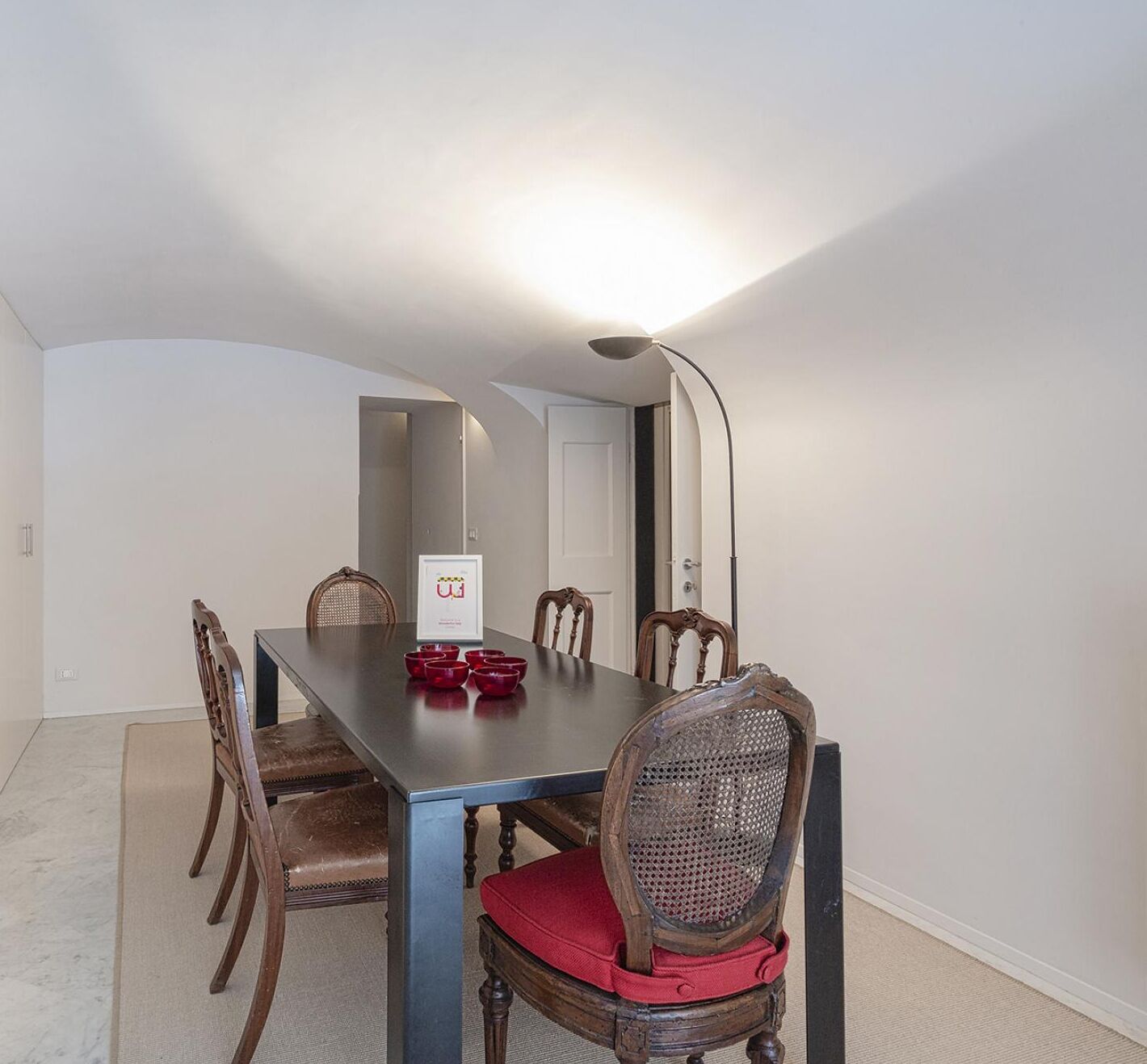 Une salle à manger avec une table rectangulaire, six chaises en bois et un luminaire moderne.