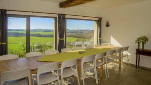 Un comedor con vistas a campos verdes, una viga de techo de madera y una mesa con sillas.