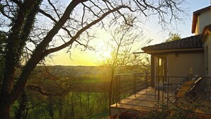 Una casa con balcón que da a un paisaje exuberante al atardecer.