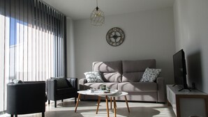 A modern living room with a sofa, two armchairs, a coffee table, and a TV stand.