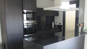 A modern kitchen with dark cabinetry, stainless steel appliances, and a central island.