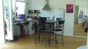Una cucina compatta con zona pranzo, pavimento in legno e un'ampia finestra.