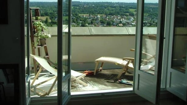 Una stanza con una porta vetrata scorrevole che dà su un balcone con vista su una zona residenziale.